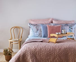 styled bed with pink quilt pillows and tray