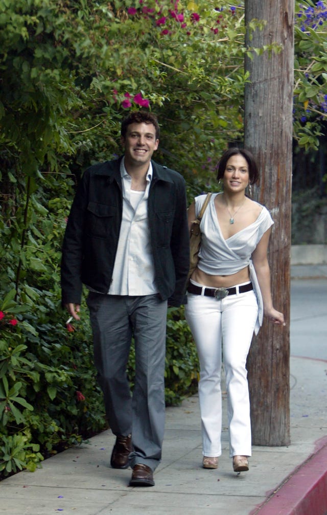 ben affleck and jennifer lopez smile while walking on a sidewalk together