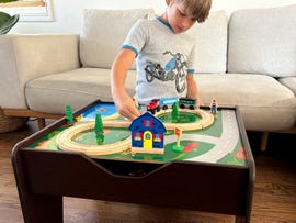 Child playing with a toy train set on a activity table