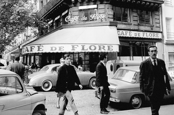 a group of men walking down a sidewalk in front of a store