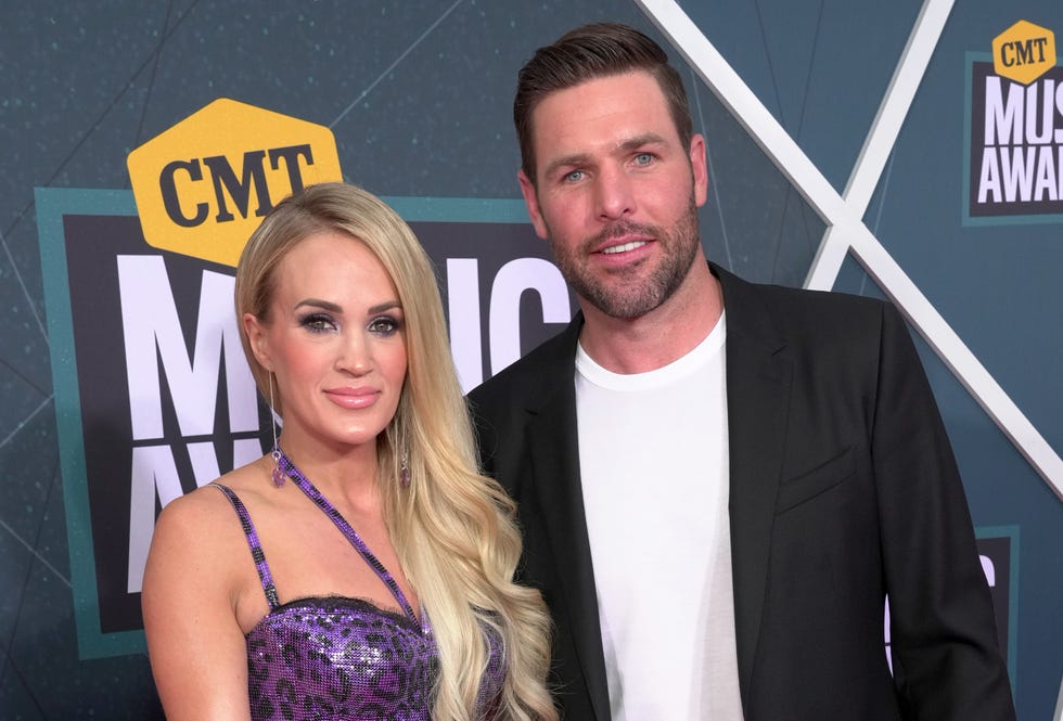 carrie underwood standing for a photo with husband mike fisher in front of a cmt backdrop