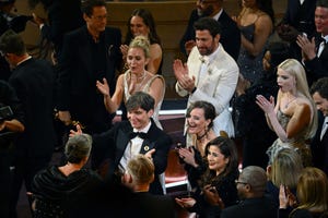 emily blunt, cillian murphy and several other people celebrate while standing and clapping