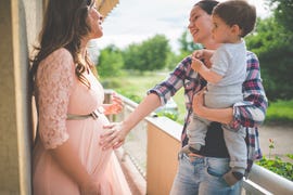 friend with child touching pregnant woman's belly