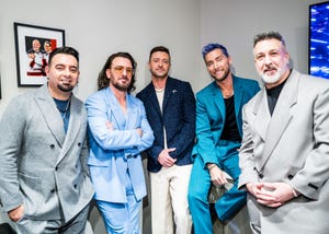 chris kirkpatrick, jc chasez, justin timberlake, lance bass, and joey fatone pose for a photo together while standing, all five men wear suits of different colors