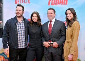 arnold schwarzenegger poses for a photo in front of a fubar backdrop with chris pratt and daughters katherine and christina