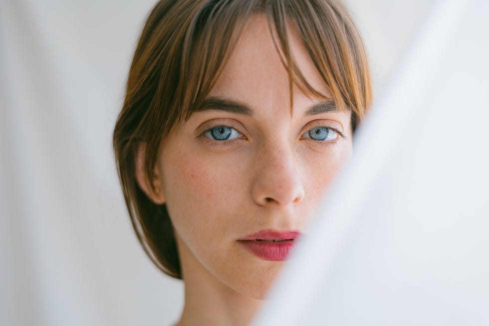 close up of a beautiful young woman with blue eyes looking at the camera with a serious face