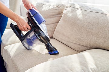 close up of woman using vacuum cleaner on couch