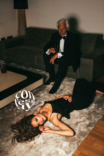a man sitting on a couch with a woman lying on the floor in front of him