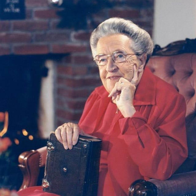 corrie ten boom sitting in a chair while resting her head in her left hand and holding a book