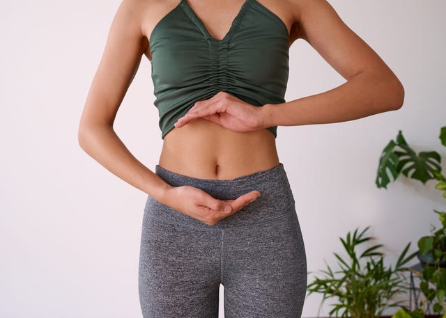 cropped shot of a young multi ethnic woman's stomach cupped by her hands