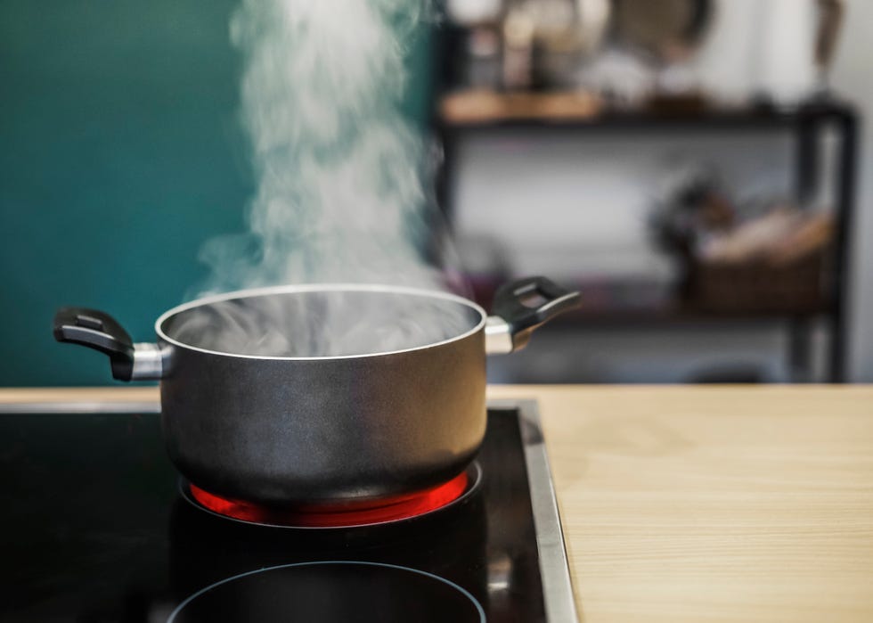 dark cooking pot with water steam on stove at kitchen background