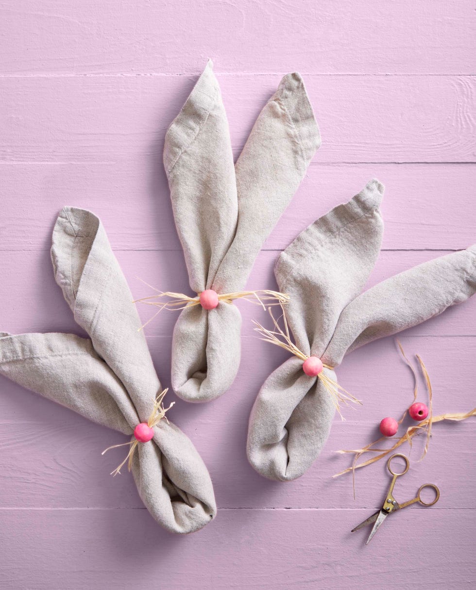 napkins folded into bunny ear shapes held together with painted wooden craft beads and raffia meant to mimic bunny noses