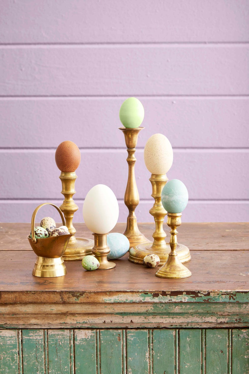 different sized easter eggs perched on vintage brass candlesticks