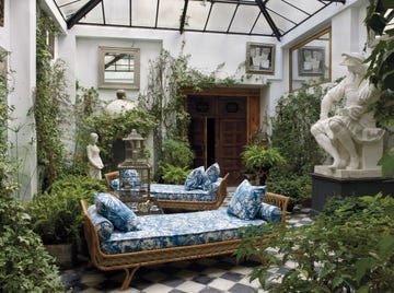 interior courtyard with two blue and white upholstered daybed and checked floor and glass panels overhead and lots of plants