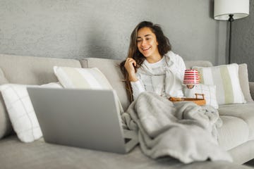 vrouw op bank met dekentje en laptop