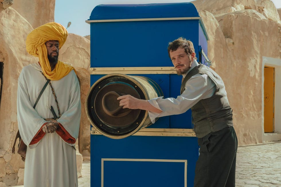 a man interacting with a vintage cameralike device in a desert setting