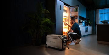 a person sitting on a stool next to a refrigerator