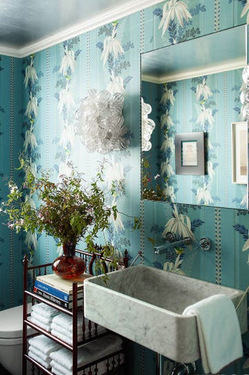 bathroom with blue floral wallpaper, black standalone shelf, marble sink, and bouquet