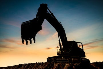 excavator at a construction site against the setting sun