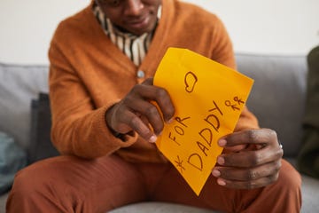 close up of african american man opening letter for daddy as handmade gift for fathers day, copy space