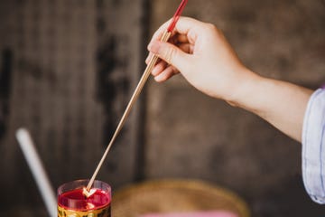 female hand burning incense at a buddhist temple