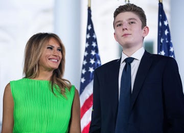 barron trump looking upward with american flags in the background