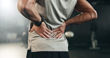 fitness, back pain and hands of man at gym for training with muscle, problem or arthritis sports, injury and guy athlete with joint massage for backache, fibromyalgia or osteoporosis accident