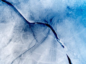 full frame of the textures formed of a block of cracked ice on a light blue color background