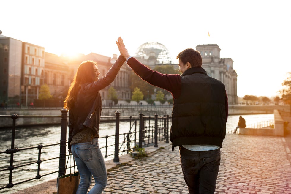 germany, berlin, young walking along river spree high fiving