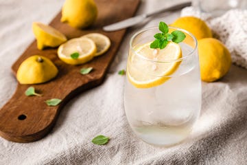 glass of lemonade over table and lemons behind