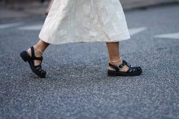 copenhagen, denmark august 10 a guest wears a matching white latte checkered embossed pattern silk midi skirt, black shiny leather meduse starppy shoes from prada, a silver watch, a black wicker handbag, gold rings, white pearls feet bracelets, outside baum und pferdgarten, during copenhagen fashion week springsummer 2023, on august 10, 2022 in copenhagen, denmark photo by edward berthelotgetty images