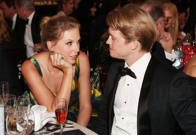 taylor swift looking at joe alwyn while they're seated together at a table