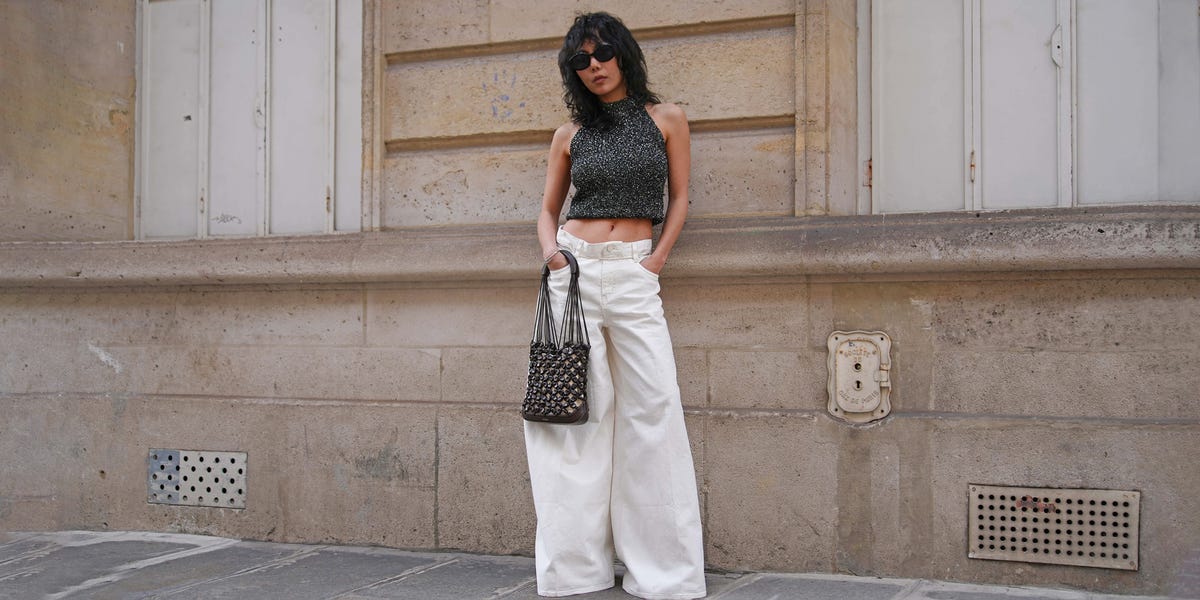 a person in a black top and white pants standing in front of a building