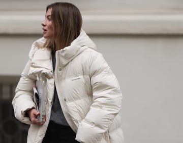 berlin, germany september 26 sophia geiss is seen wearing a silver nose ring an outfit from moco consisting of an ankle length white quilted jacket, a grey pullover with a ribbed v neckline underneath, and a black pleated mini skirt a silver minimalist ring and knee high chunky black leather boots from leger while carrying a macbook and a newspaper on september 26, 2024 in berlin, germany photo by jeremy moellergetty images