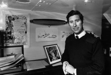 charles, prince of wales as a lieutenant in the royal navy, poses beside a photograph of his queen elizabeth the queen mother in his cabin aboard hms bronington