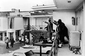 Andrew Young and others standing on balcony of Lorraine Motel pointing in direction of assailant after assassination of civil rights leader Martin Luther King Jr., who is lying at their feet.