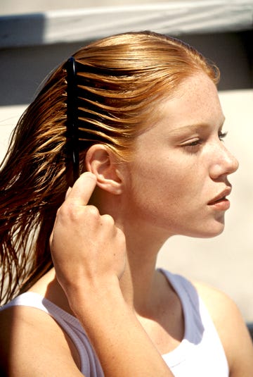 young woman combing her hair, outdoors