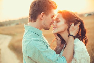 Young couple in love outdoor.in summer in field. Couple hugging. Young beautiful couple in love staying and kissing on the field on sunset. Soft sunny colors.