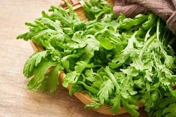 green leaves bunch crown daisy or garland chrysanthemum glebionis coronaria in wood plate on wooden table background tong ho, shungiku