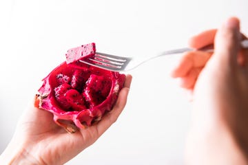 hand holding fork for eating red dragon fruit