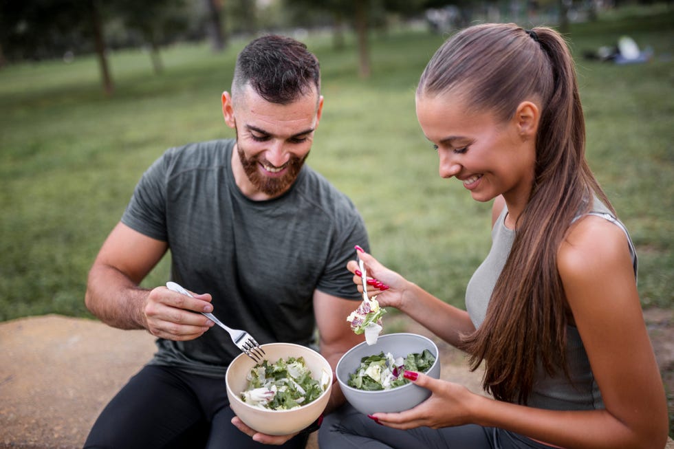 happy sporty couple eating vegetable salad after intensive workout