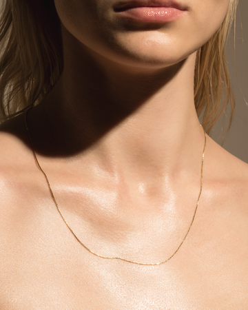 Closeup of a person showing a gold necklace and smooth skin