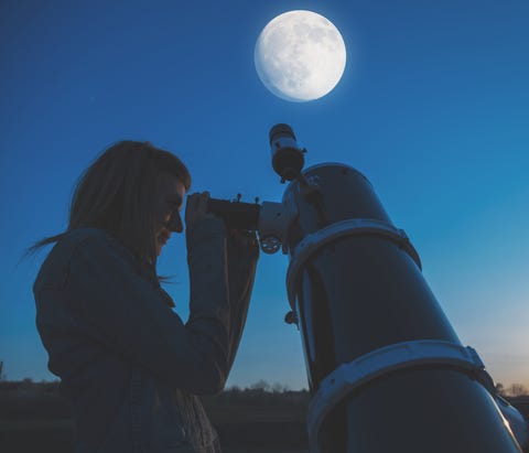girl looking at a full moon through a telescope