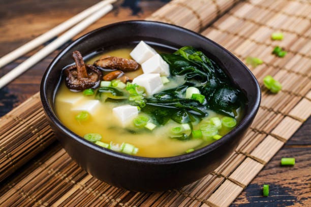 traditional miso soup with wakame seaweeds, tofu and shiitake mushrooms on bamboo mat copy space