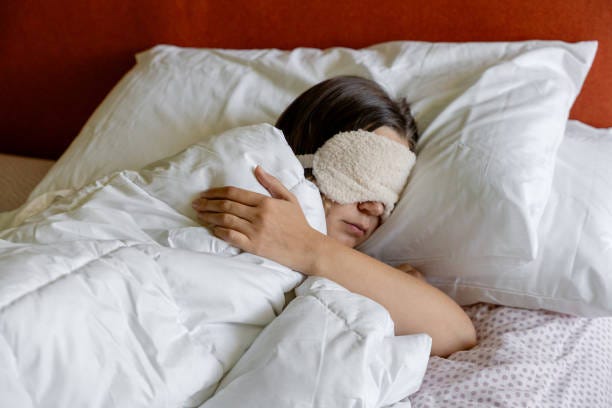 a woman sleeping with a eye sleeping mask on her head