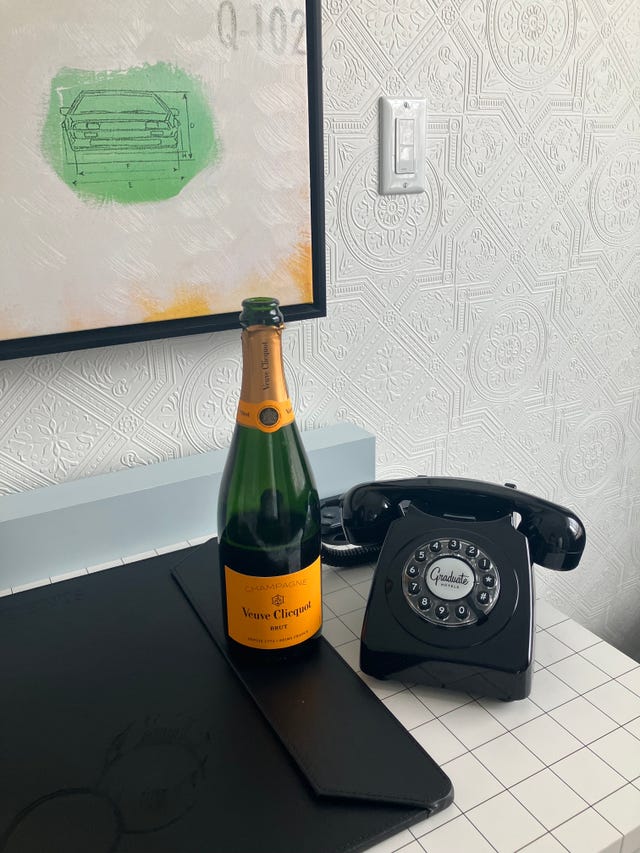 a bottle of champagne and a black rotary phone in a hotel room