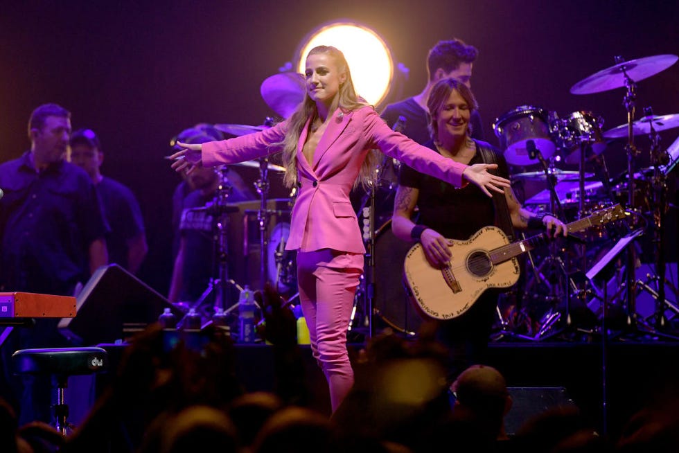 ingrid andress and keith urban perform on stage with band members in the background