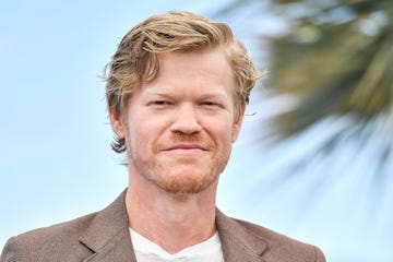 actor jesse plemons smiling for a photo with palm leaves in the background