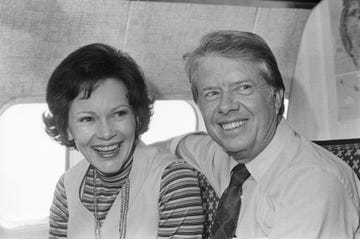 jimmy carter and rosalynn carter smile and look past the camera while sitting on an airplace