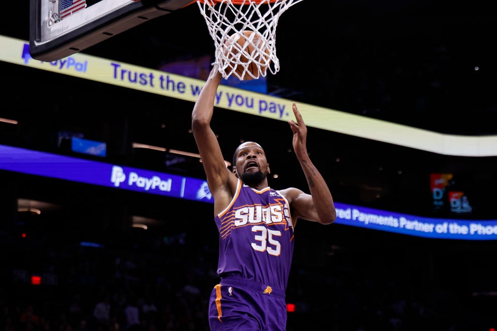 kevin durant jumping up toward a basketball hoop while holding a ball